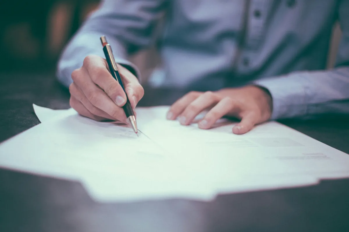 Person completing paperwork with a pen for a France Talent Passport family file
